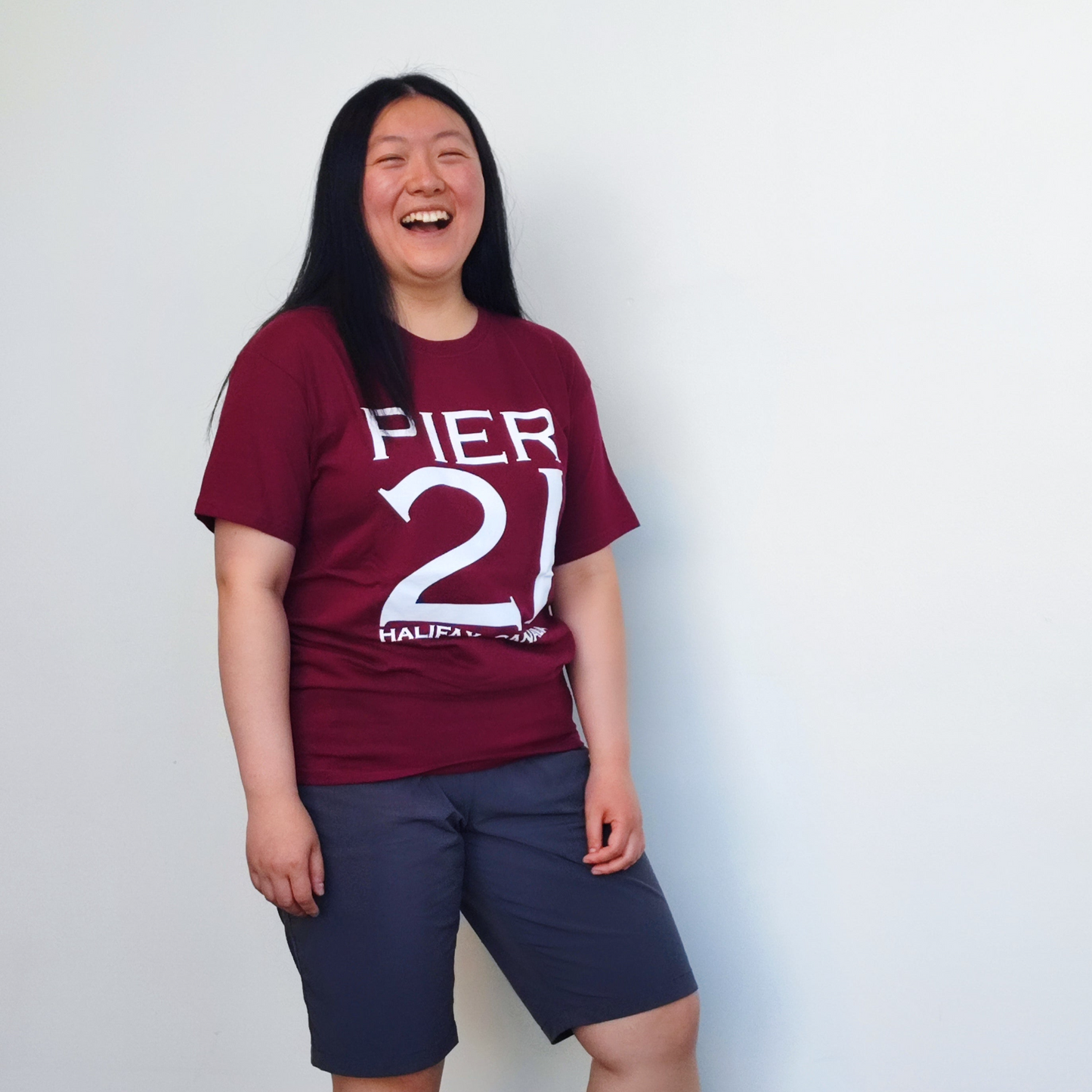 Female model wearing burgundy Pier 21 shirt against a white wall