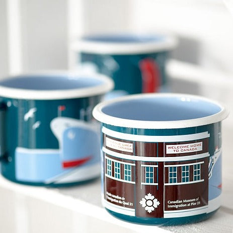 Three enamel mugs, the one in front is in focus and the other two are blurred.
