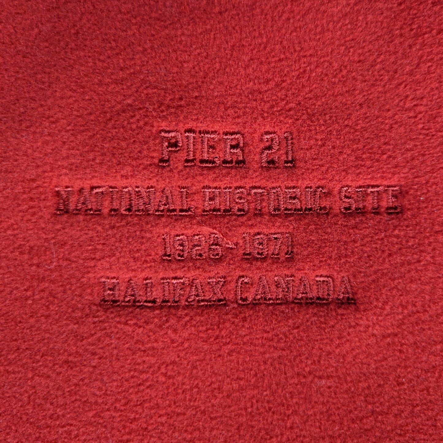 Close up of embroidery on right breast that says Pier 21 National Historic Site 1945-1971 Halifax Canada 