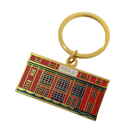 Enamel keychain of the façade of Pier 21 in orange, teal, navy and gold