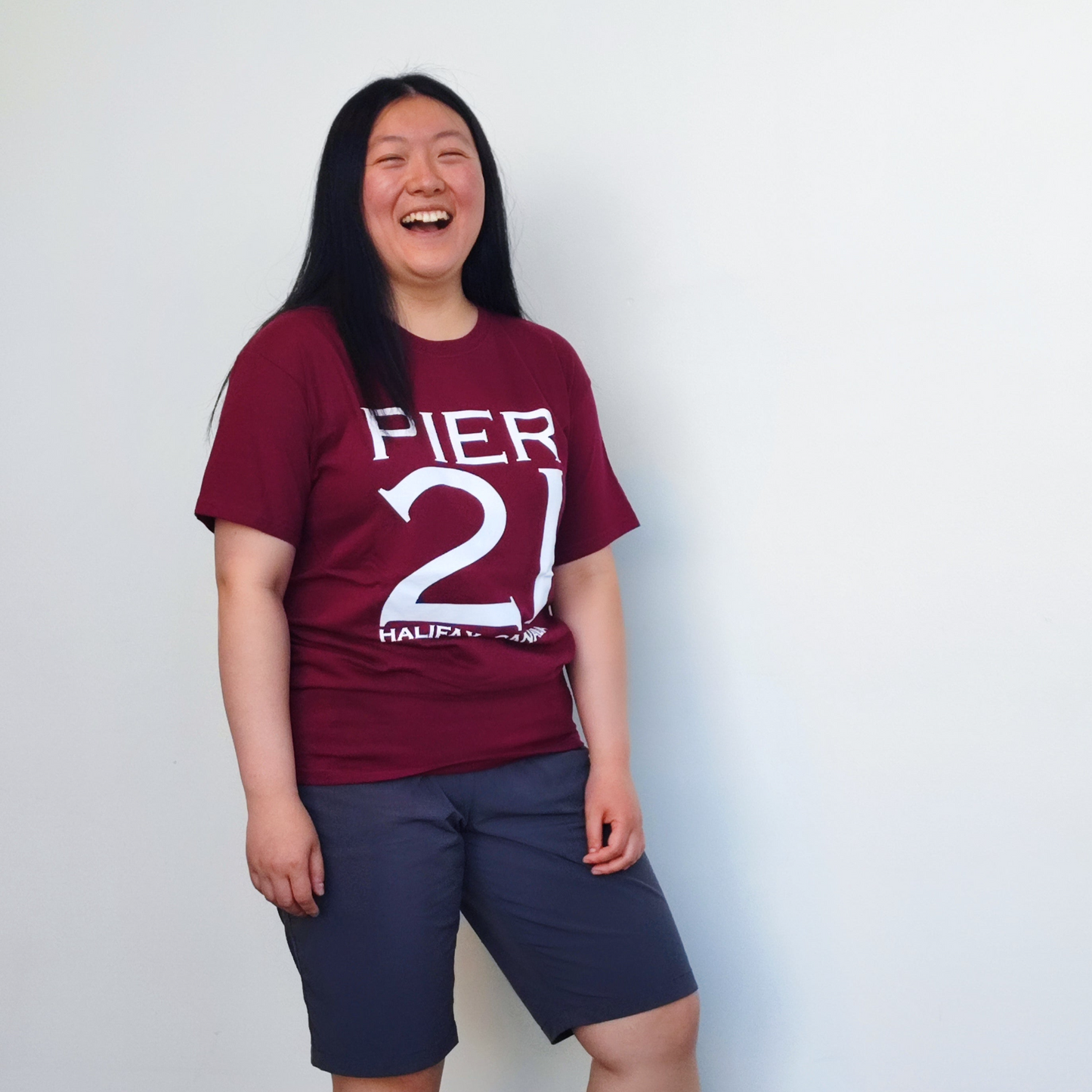 Female model wearing burgundy Pier 21 shirt against a white wall 