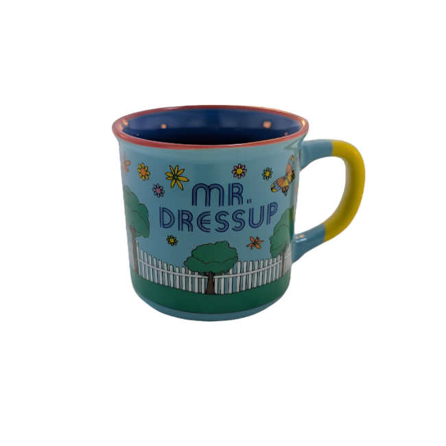 Right view of mug with trees, flowers, a butterfly and a white picket fence surrounding the name, Mr. Dressup 