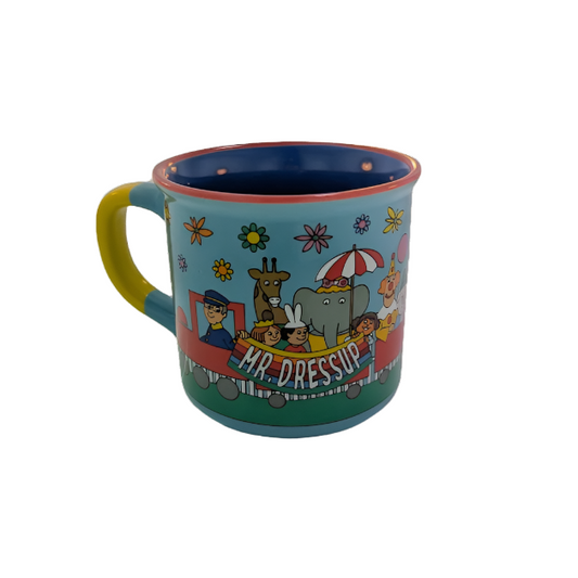 Left view of mug featuring a train being pulled by Mr. Dressup with animals, children and a clown holding up a banner with his name on it. 