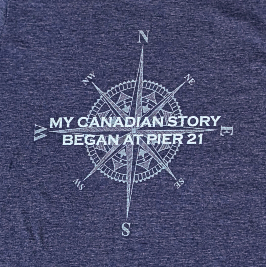 Close up of navy shirt with compass rose graphic with words, My Canadian Story Began at Pier 21 