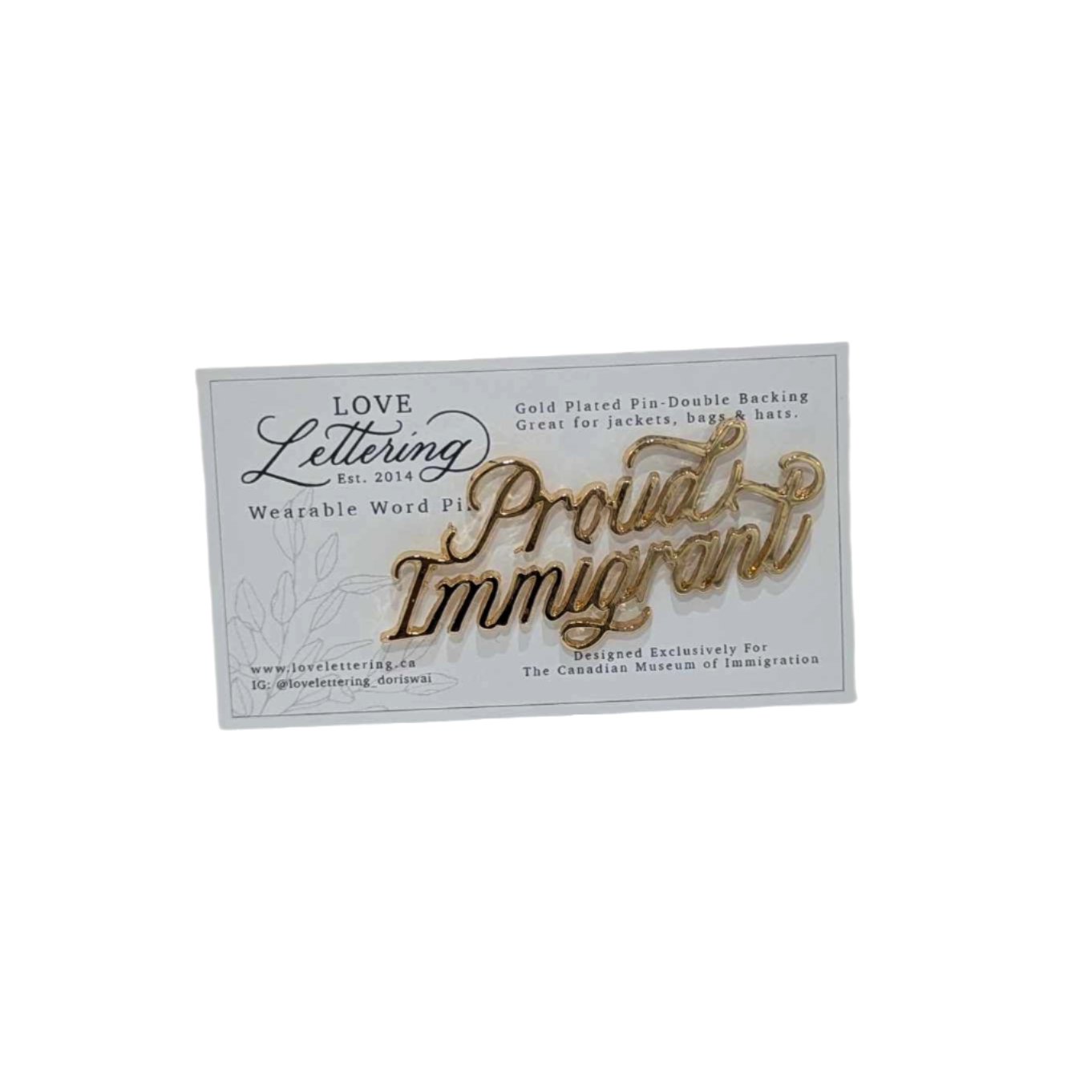 Proud Immigrant pin in gold plating on top of backing card with supplier's information 