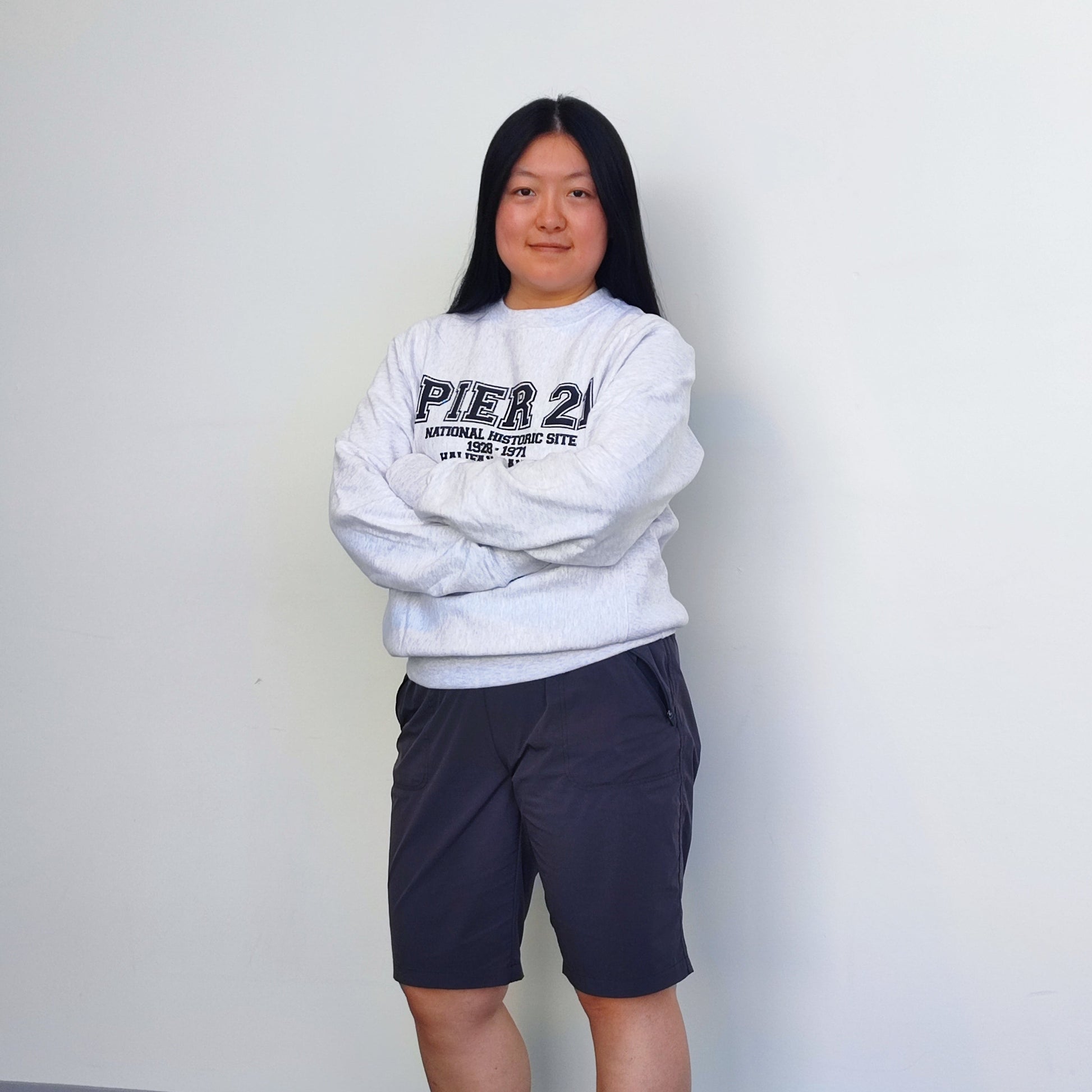 Female model wearing Pier 21 sweatshirt with arms crossed